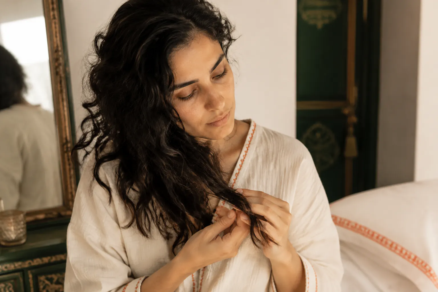 Femme observant les pointes de ses cheveux ondulés devant un miroir