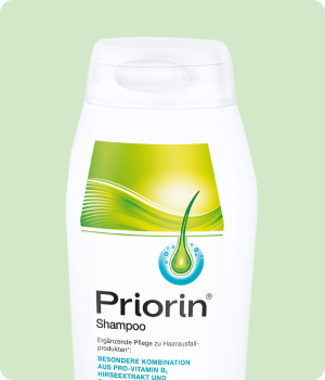 Une bouteille de shampoing priorin sur fond vert.