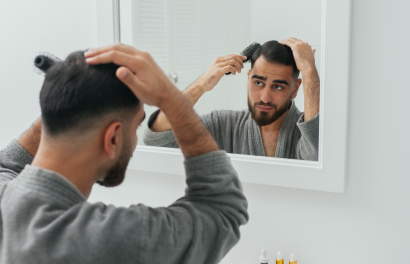 Un homme se brosse les cheveux devant un miroir.