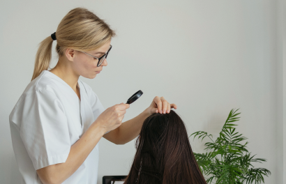 Une femme examine ses cheveux avec une loupe.