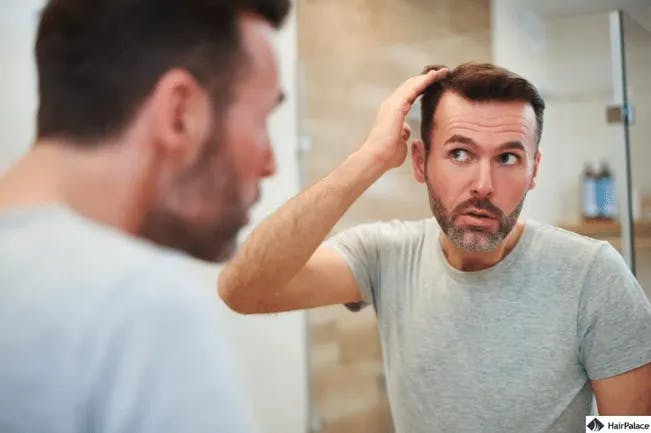 Un homme se brosse les cheveux devant un miroir.