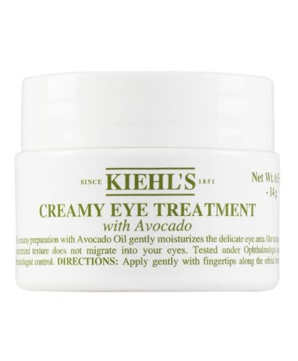 Un pot blanc étiqueté "Kiehl's - Creamy Eye Treatment With Avocado, 14g" présente les détails du produit et les instructions d'application sur le devant.