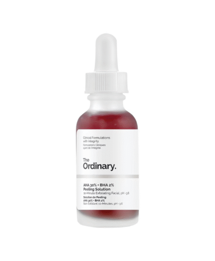 Un flacon compte-gouttes en verre transparent étiqueté "The Ordinary - AHA 30% + BHA 2% Solution de Peeling, 30 ml", rempli de liquide rouge, se tient debout sur un fond blanc.
